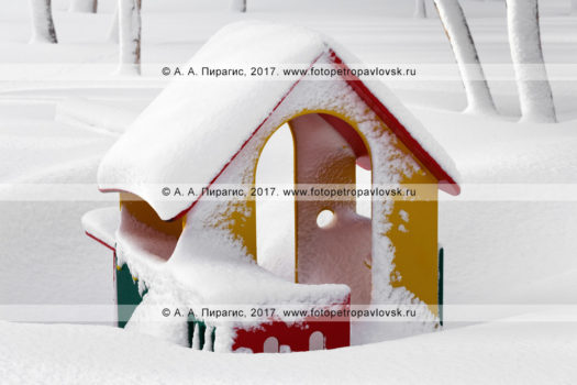 Фотография: занесенный снегом детский уличный игровой домик, детская игровая площадка в парке зимой