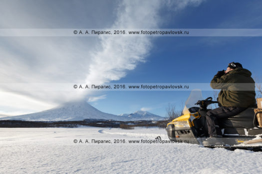 Фотография: камчатский турист и путешественник на снегоходе фотографирует действующий Ключевской вулкан на Камчатке