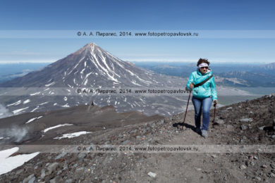 Фотография девушки поднимающейся на вершину Авачинского вулкана на фоне Корякского вулкана