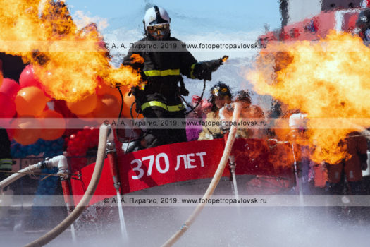 Парящий в воздухе пожарный-спасатель с огнеметами, извергающими пламя. День пожарной охраны Российской Федерации
