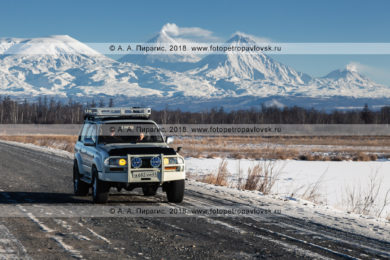 Фотографии: автомобили едут по автотрассе на фоне Ключевской группы вулканов на полуострове Камчатка