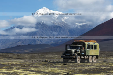 Фотография: туристический экспедиционный автомобиль высокой проходимости ЗИЛ-вахтовка припаркован, в ожидании туристов и путешественников, на Толбачинском долу на фоне вулкана Острый Толбачик. Полуостров Камчатка