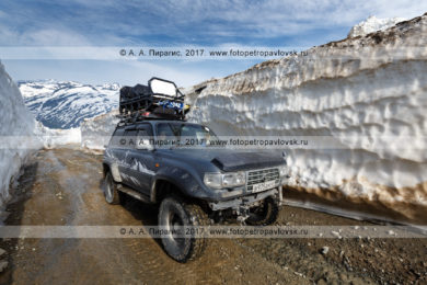 Фотография: японский полноприводный автомобиль Toyota Land Cruiser едет по горной дороге в многометровом снежном тоннеле на Вилючинском перевале на полуострове Камчатка