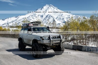 Фотография: японский внедорожный автомобиль Nissan Safari (Ниссан Сафари) едет по дороге на фоне Вилючинского вулкана на полуострове Камчатка