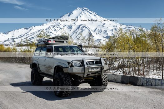 Фотография: японский внедорожный автомобиль Nissan Safari (Ниссан Сафари) едет по дороге на фоне Вилючинского вулкана на полуострове Камчатка