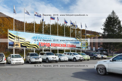 Фотография: плакат "Петропавловск-Камчатский — город воинской славы" и флагштоки с флагами России, Камчатского края и Петропавловск-Камчатского городского округа